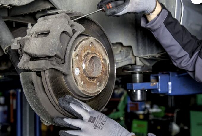 Mecânico trabalhando no freio de um carro na oficina